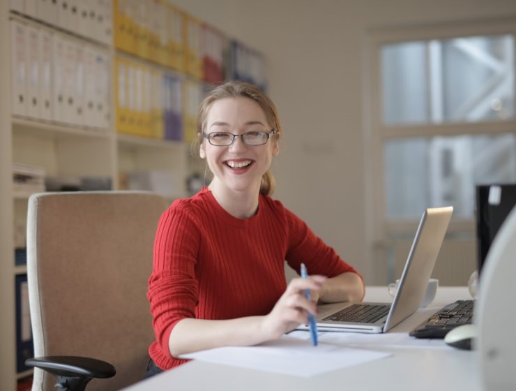doctoral-candidate-in-red-sweater-leaning-on-white-table